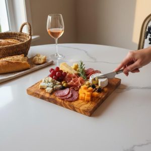 Square olive wood cutting board used as a charcuterie serving board