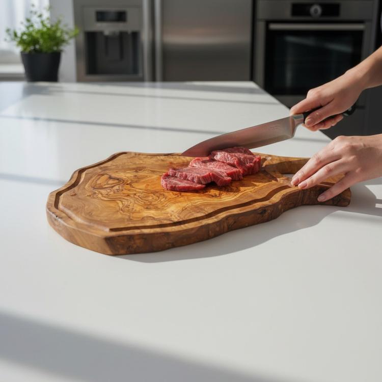 Irregular olive wood chopping board with groove being used to prepare steak