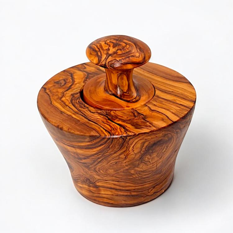 Close-up of olive wood garlic mortar and pestle showing distinctive swirling grain patterns