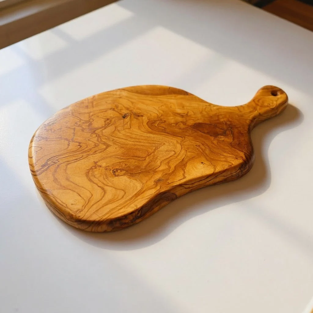Natural olive wood freeform charcuterie board with handle showing distinctive swirling grain and organic live edge
